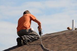 Building contractor putting the asphalt roofing on a large commercial apartment building development